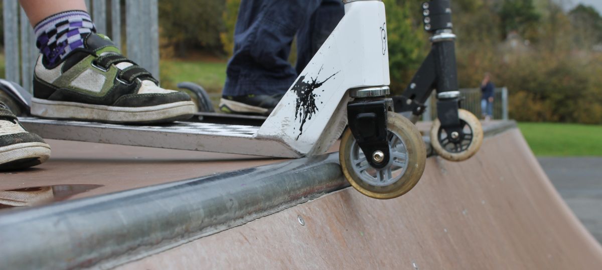 Подросток держит самокат над горкой